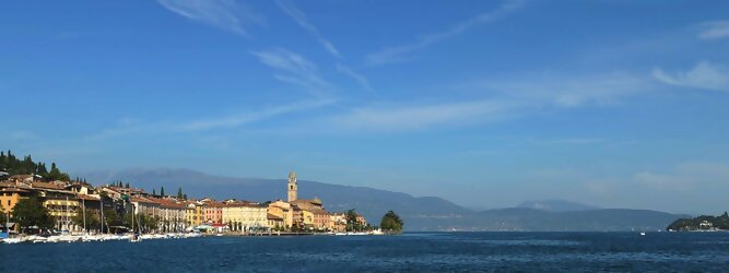 Trip Kreuzfahrt beliebte Urlaubsziele am Gardasee -  Mit einer Fläche von 370 km² ist der Gardasee der größte See Italiens. Es liegt am Fuße der Alpen und erstreckt sich über drei Staaten: Lombardei, Venetien und Trentino. Die maximale Tiefe des Sees beträgt 346 m, er hat eine längliche Form und sein nördliches Ende ist sehr schmal. Dort ist der See von den Bergen der Gruppo di Baldo umgeben. Du trittst aus deinem gemütlichen Hotelzimmer und es begrüßt dich die warme italienische Sonne. Du blickst auf den atemberaubenden Gardasee, der in zahlreichen Blautönen schimmert - von tiefem Dunkelblau bis zu funkelndem Türkis. Majestätische Berge umgeben dich, während die Brise sanft deine Haut streichelt und der Duft von blühenden Zitronenbäumen deine Nase kitzelt. Du schlenderst die malerischen, engen Gassen entlang, vorbei an farbenfrohen, blumengeschmückten Häusern. Vereinzelt unterbricht das fröhliche Lachen der Einheimischen die friedvolle Stille. Du fühlst dich wie in einem Traum, der nicht enden will. Jeder Schritt führt dich zu neuen Entdeckungen und Abenteuern. Du probierst die köstliche italienische Küche mit ihren frischen Zutaten und verführerischen Aromen. Die Sonne geht langsam unter und taucht den Himmel in ein leuchtendes Orange-rot - ein spektakulärer Anblick.